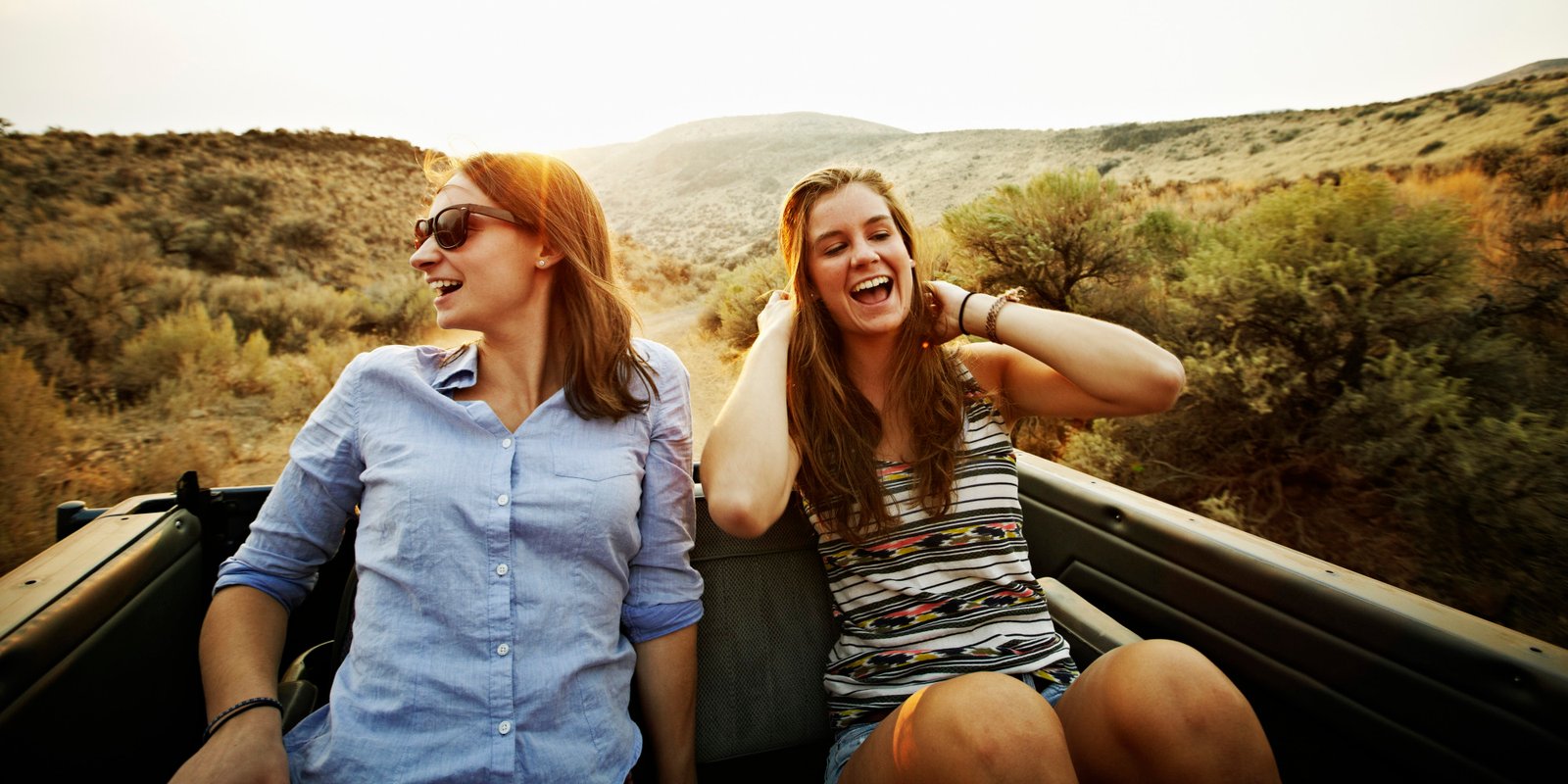 Two friends riding in the backseat of convertible